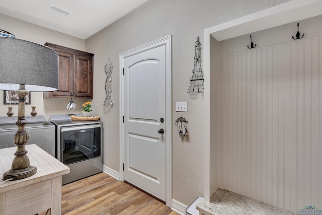 laundry room featuring light wood finished floors, visible vents, independent washer and dryer, baseboards, and cabinet space