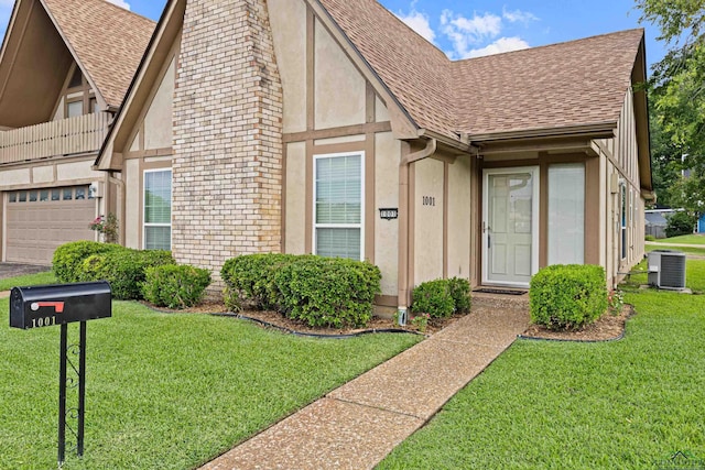 1001 Towne Lake Dr, Longview, TX 75601 - tudor home featuring roof with shingles, stucco siding, an attached garage, and a front yard