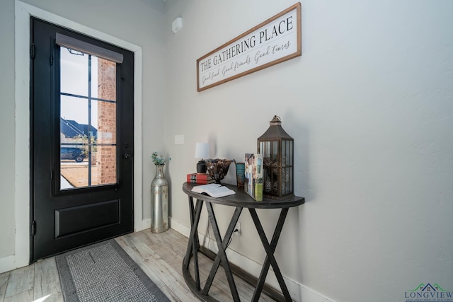 doorway to outside featuring light wood finished floors and baseboards