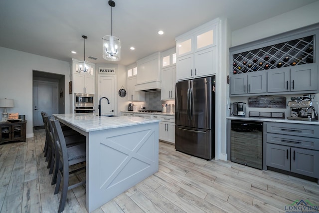 kitchen featuring white cabinets, wine cooler, glass insert cabinets, appliances with stainless steel finishes, and decorative light fixtures