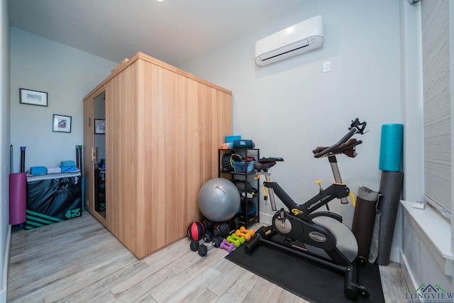 exercise room featuring a wall mounted air conditioner and light wood-style floors