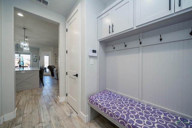 mudroom with visible vents, baseboards, light wood-style flooring, and a notable chandelier