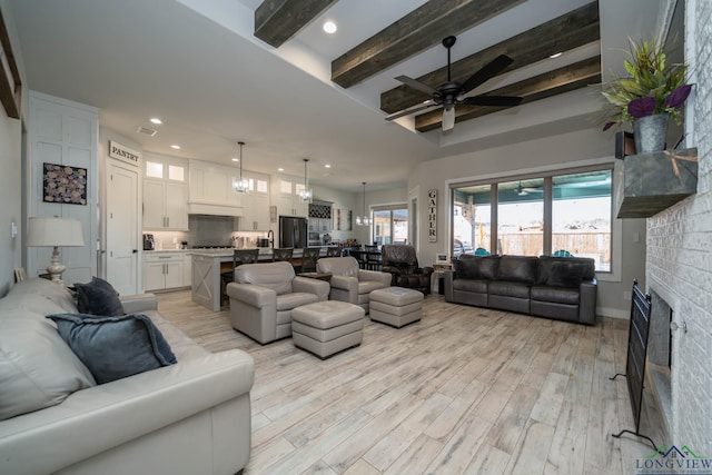 living room featuring light wood finished floors, a fireplace, beamed ceiling, and recessed lighting