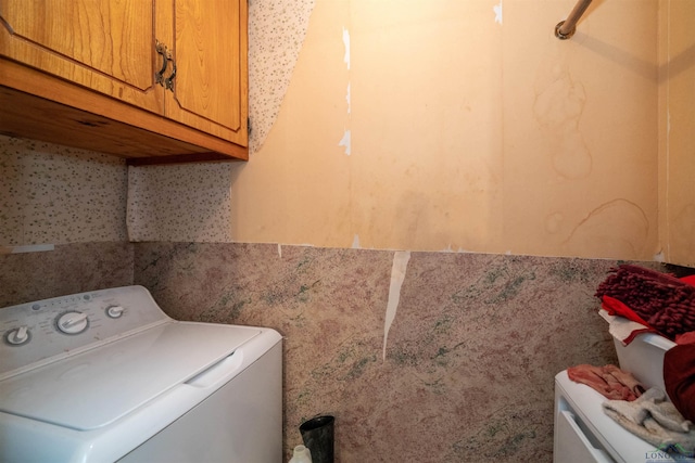 clothes washing area featuring washer / clothes dryer and cabinets