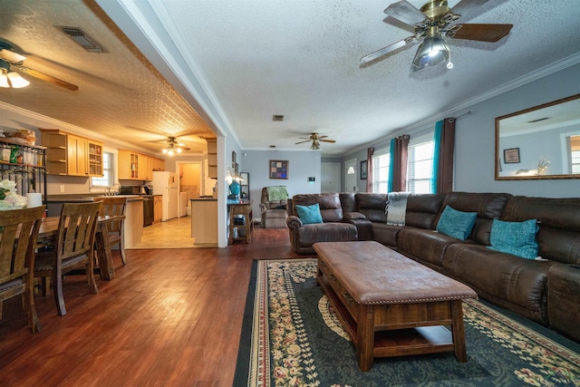 living room with dark wood-type flooring, ornamental molding, and a textured ceiling