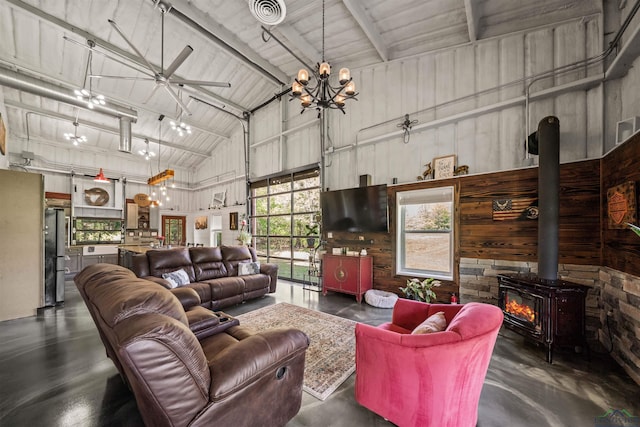 13391 County Road 4336, Larue, TX 75770 - living room featuring high vaulted ceiling, finished concrete floors, a wood stove, a chandelier, and wood walls