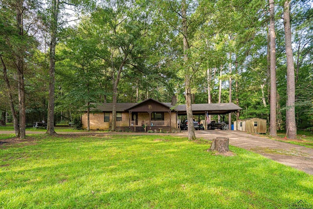 view of front of house with covered porch, a front lawn, a shed, and a carport