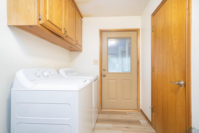 laundry room featuring light hardwood / wood-style floors, cabinets, separate washer and dryer, and a textured ceiling