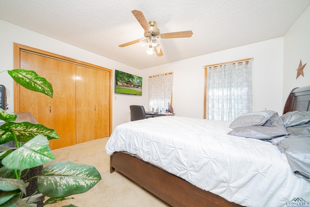 carpeted bedroom featuring a textured ceiling, a closet, and ceiling fan