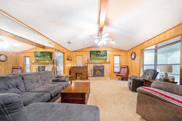 carpeted living room featuring ceiling fan, a fireplace, lofted ceiling with beams, and a textured ceiling