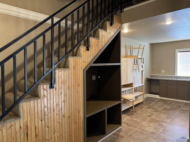 staircase featuring sink and tile patterned flooring