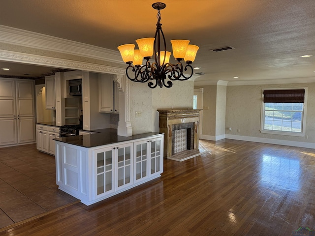 kitchen featuring kitchen peninsula, decorative light fixtures, a chandelier, white cabinetry, and range with gas stovetop