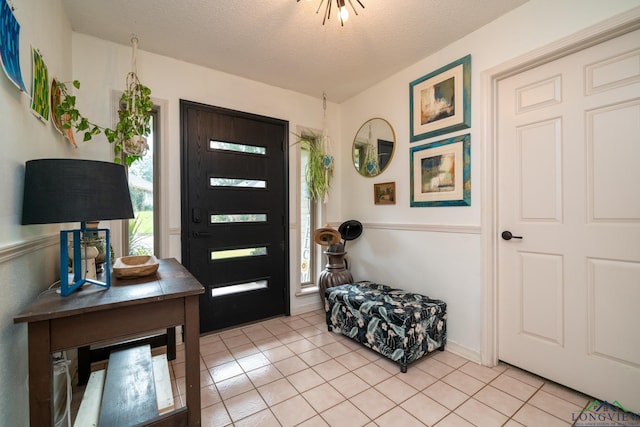 entryway with light tile patterned flooring and a textured ceiling