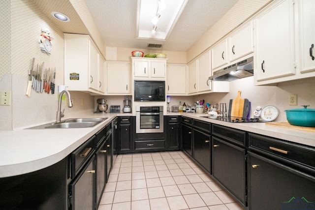 kitchen featuring white cabinetry, sink, light tile patterned floors, and black appliances