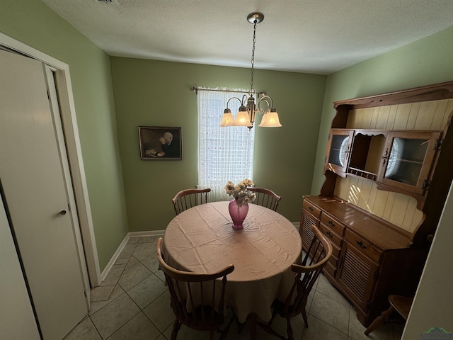 tiled dining space featuring a textured ceiling and an inviting chandelier