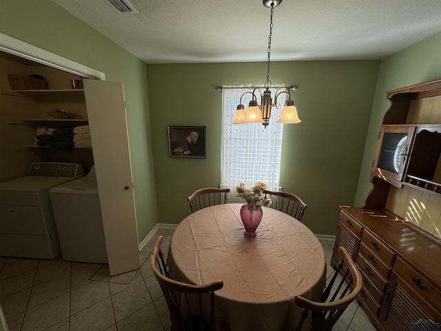 dining room featuring washing machine and clothes dryer, light tile patterned flooring, a textured ceiling, and a notable chandelier