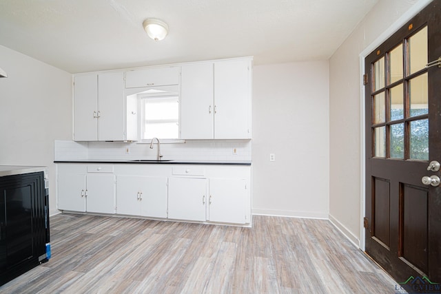 kitchen featuring white cabinets, light hardwood / wood-style floors, sink, and tasteful backsplash