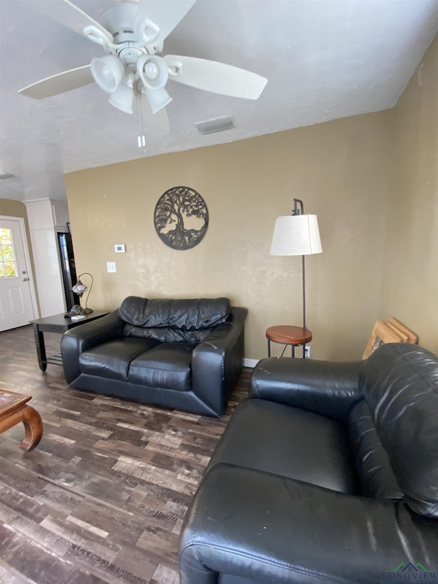 living area featuring dark wood-style flooring, visible vents, and a ceiling fan