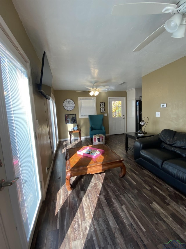 living area with dark wood-style floors, baseboards, and a ceiling fan