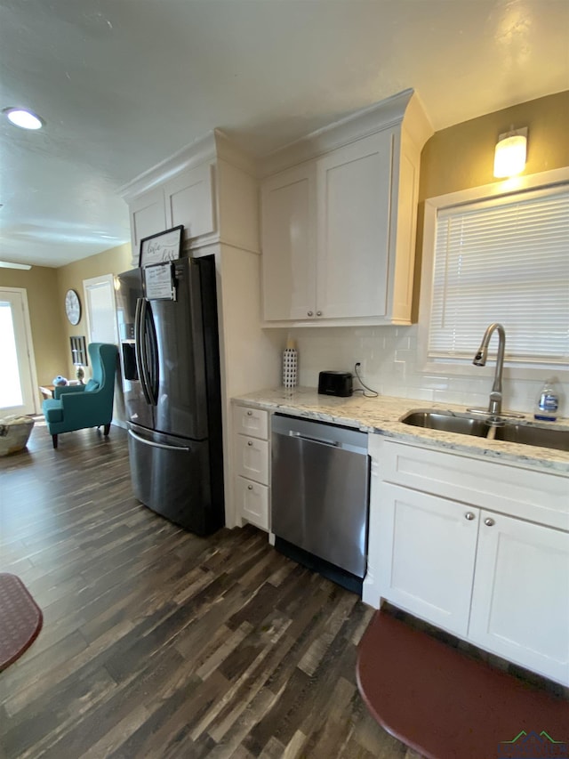 kitchen with dark wood-style flooring, light stone countertops, stainless steel appliances, white cabinetry, and a sink