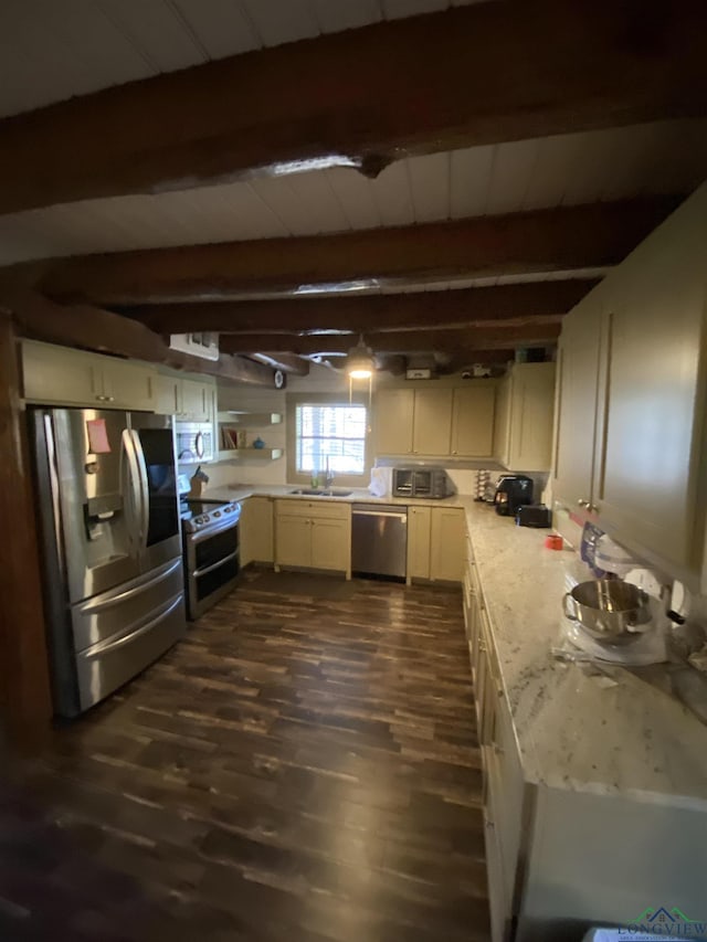 kitchen featuring dark wood-style flooring, cream cabinets, appliances with stainless steel finishes, a sink, and beamed ceiling