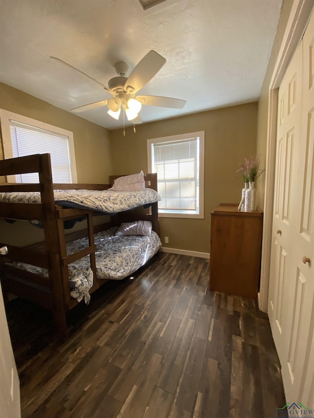 bedroom with baseboards, a closet, a ceiling fan, and dark wood-type flooring