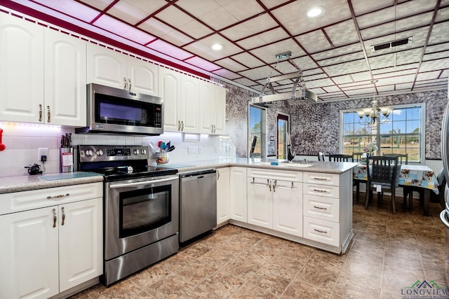 kitchen featuring a chandelier, stainless steel appliances, backsplash, and white cabinetry