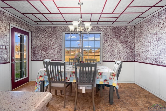 dining room with a wainscoted wall, a notable chandelier, and wallpapered walls