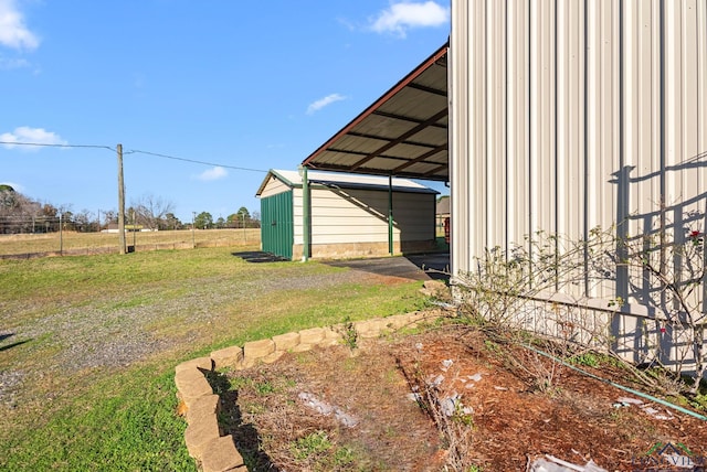 view of yard with a shed, fence, a carport, and an outdoor structure