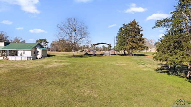 view of yard featuring a carport and an outdoor pool