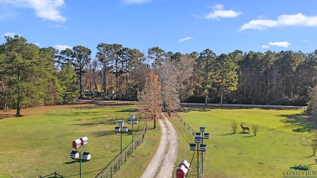 view of community with a forest view, a yard, fence, and a rural view