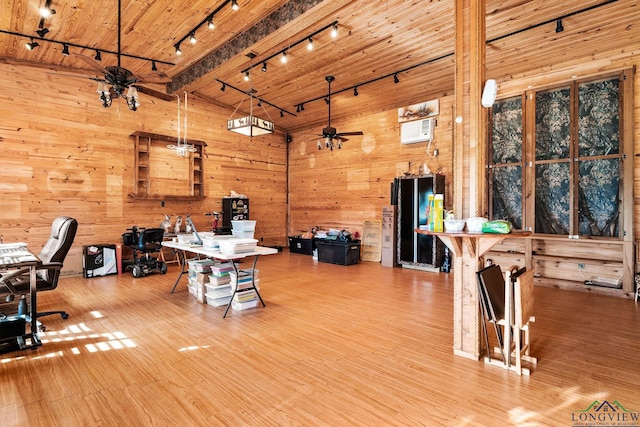 office space with wood walls, ceiling fan, high vaulted ceiling, and wood finished floors