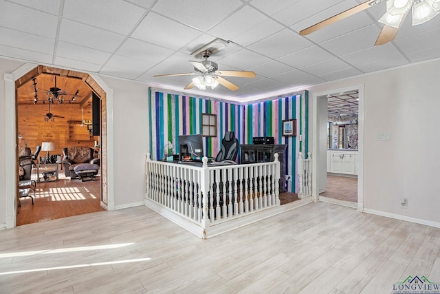 interior space featuring a paneled ceiling, ceiling fan, arched walkways, and wood finished floors