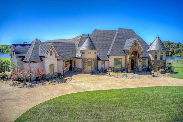 view of front of home with a water view and a front lawn