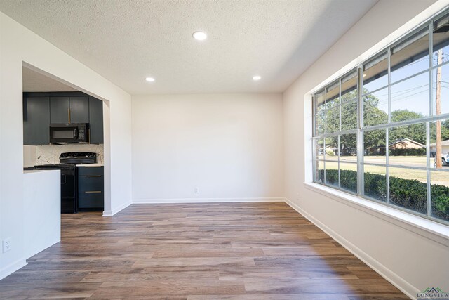 unfurnished dining area featuring light wood-type flooring and a textured ceiling