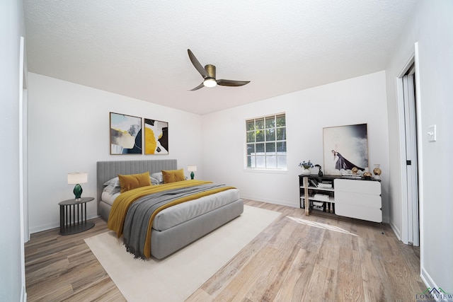 bedroom with ceiling fan, a textured ceiling, and light hardwood / wood-style flooring