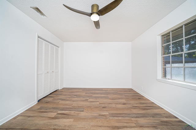 unfurnished bedroom featuring a closet, ceiling fan, hardwood / wood-style floors, and a textured ceiling