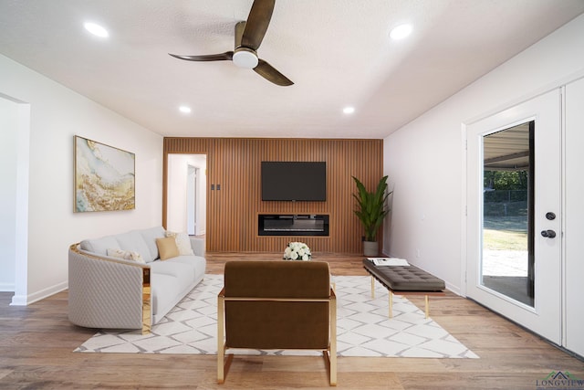 living room with a large fireplace, light hardwood / wood-style floors, and ceiling fan