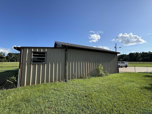 view of pole building with a lawn and fence