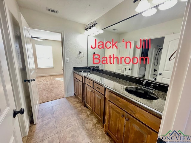 bathroom with toilet, vanity, and tile patterned floors