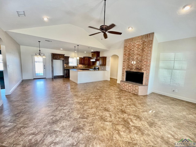 unfurnished living room with ceiling fan, high vaulted ceiling, and a fireplace