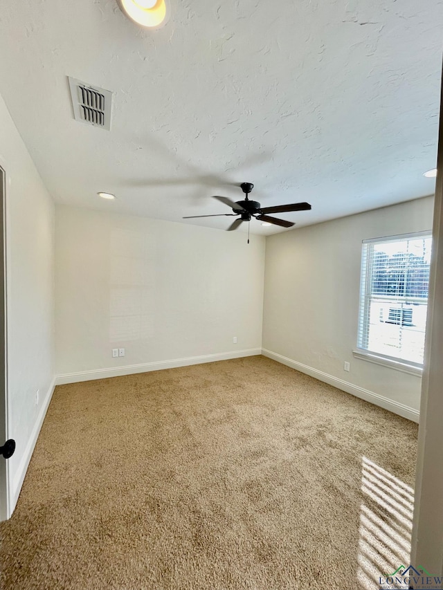 carpeted spare room with a textured ceiling and ceiling fan