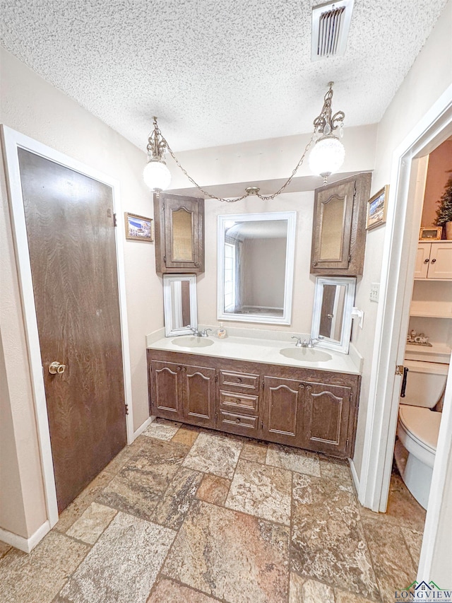 300 Delwood Dr, Longview, TX 75605 - bathroom featuring baseboards, visible vents, a sink, and a textured ceiling