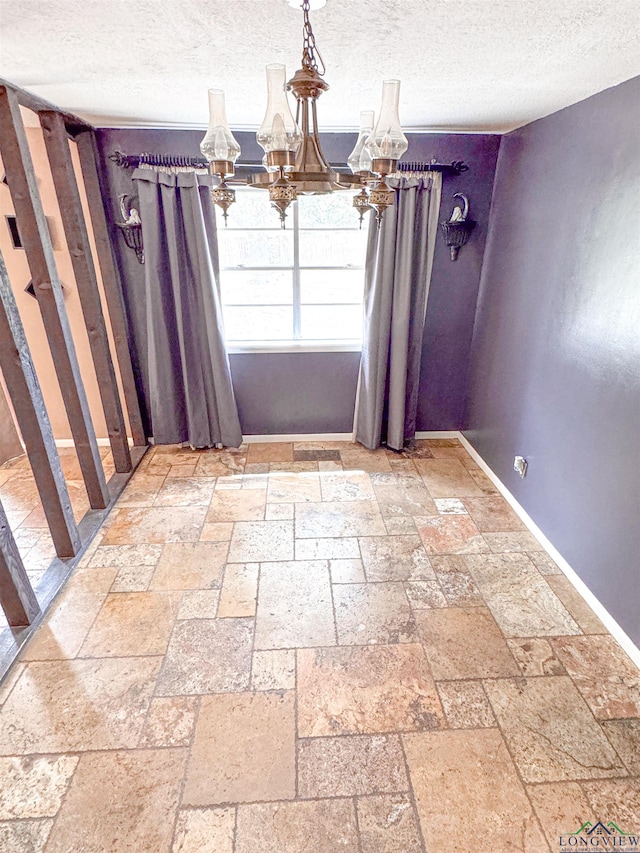 300 Delwood Dr, Longview, TX 75605 - unfurnished dining area with an inviting chandelier, stone tile flooring, baseboards, and a textured ceiling