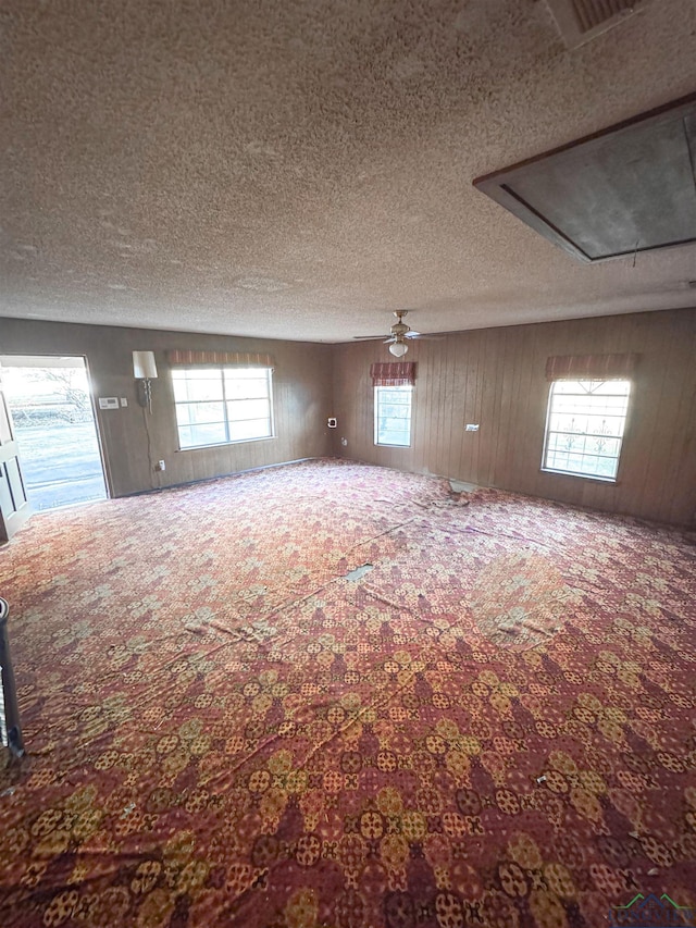 300 Delwood Dr, Longview, TX 75605 - carpeted spare room featuring attic access, a textured ceiling, wooden walls, visible vents, and a ceiling fan