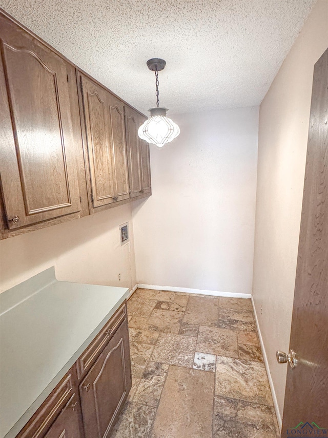 300 Delwood Dr, Longview, TX 75605 - clothes washing area with baseboards, cabinet space, a textured ceiling, and stone tile flooring