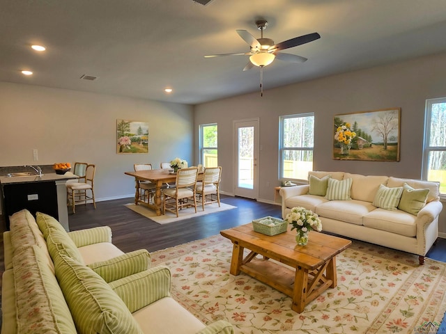 living area with dark wood-type flooring, a wealth of natural light, visible vents, and recessed lighting