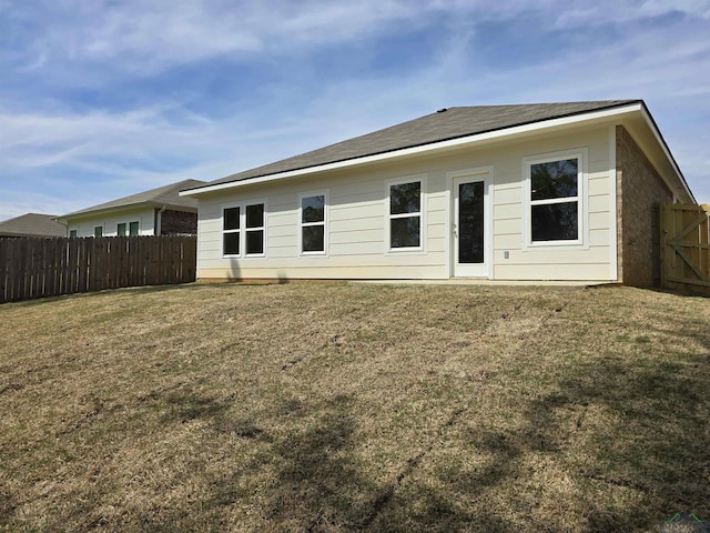 rear view of property with a fenced backyard and a lawn