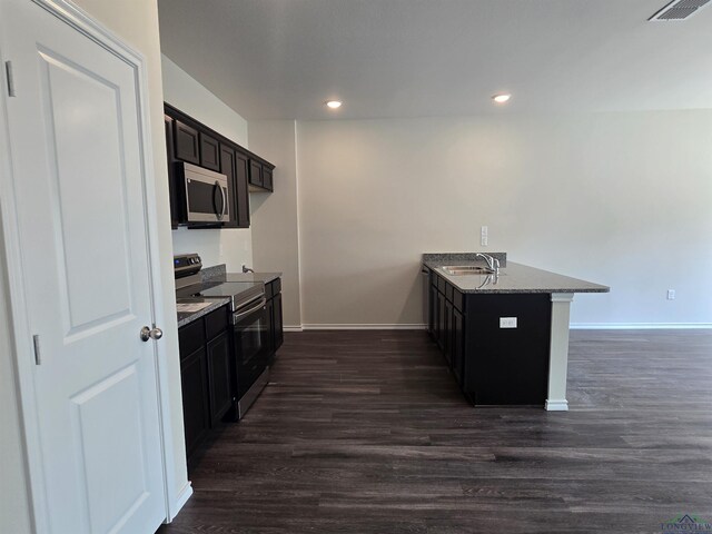 kitchen featuring stainless steel appliances, dark wood-type flooring, baseboards, a sink, and a peninsula