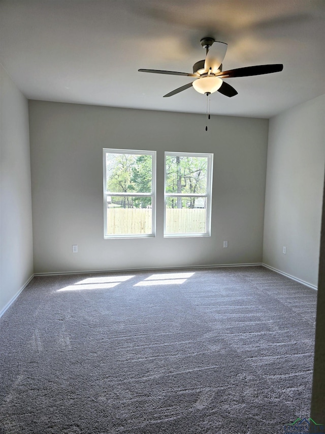 carpeted spare room with a ceiling fan and baseboards